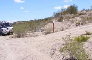 A dusty road with a single white truck parked on it