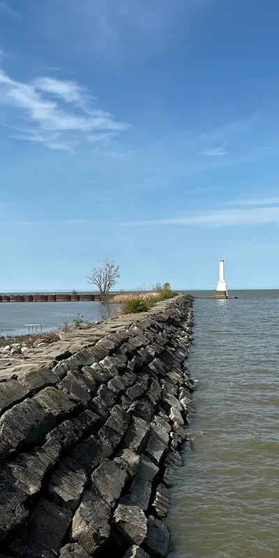 A long run of rocks running out to a light house in a lake