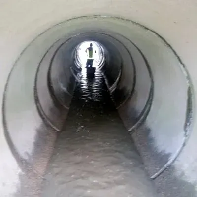 A long pipe with a technician on the far side