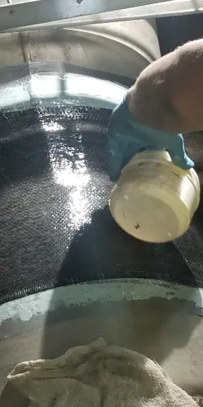 Carbon fiber fabric wrapped around a 20-inch pipe being saturated with resin