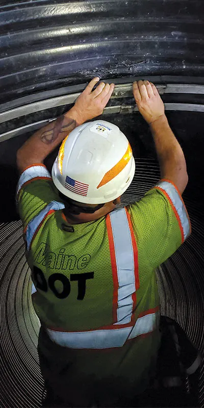 A technician adjusting the retaining band of a HydraTite seal installed over a joint in a corrugated metal pipe