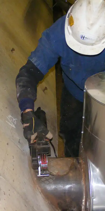 A technician working on a portion of cast iron pipe