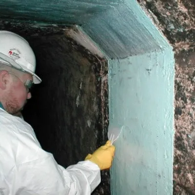 A technician applying epoxy to the interior of a concrete box tunnel