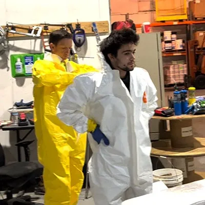 A technician assisting another with their tyvek
