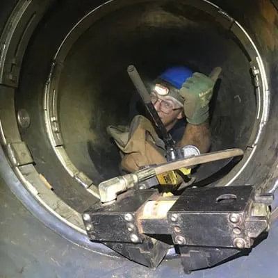 A technician workin in a small-diameter pipe to install HydraTite over a joint