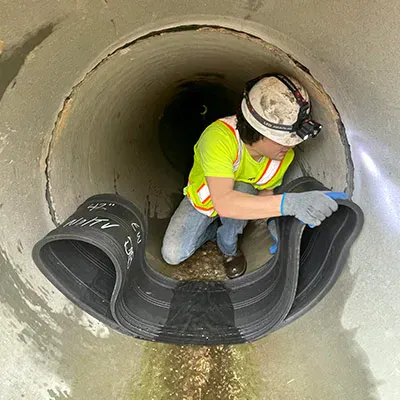 A technician positions the rubber of the HydraTite seal over a joint in this concrete pipe