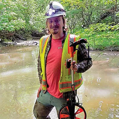 A technician standing in water holding a measuring device