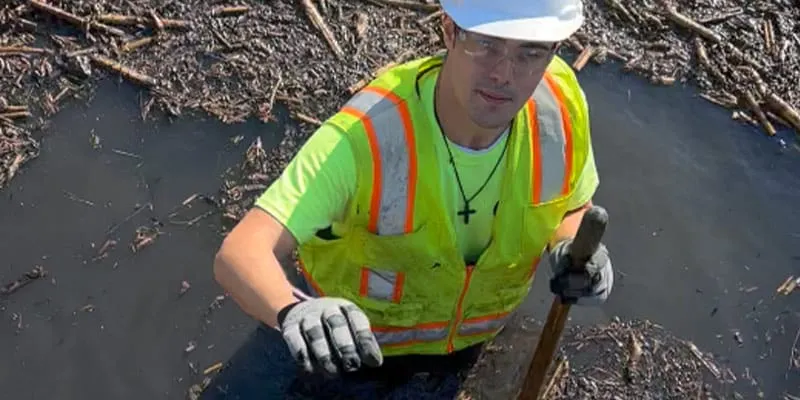 Looking down on a technician standing in deep water near a culvert entrance
