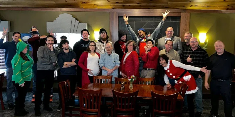 A large group of employees gathering for the yearly Christmas lunch, all of whom are making funny faces