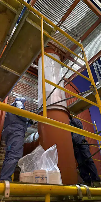 A technician applying epoxy to the exterior of a vertical digester mixing pipe