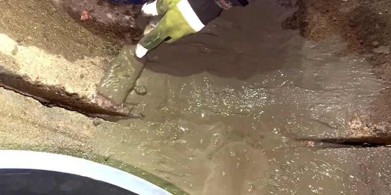 Applying concrete to the invert of a pipe near a joint