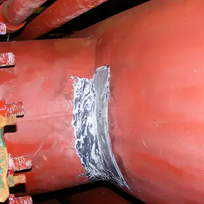 A corner of a tee fitting in a copper nickel pipe that has had the surface ground clean