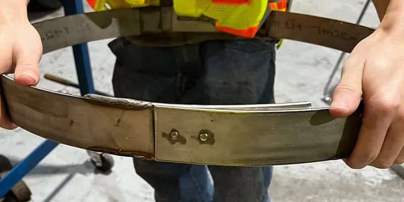 A technician expanding and contracting a retaining band to demonstrate its variable diameter