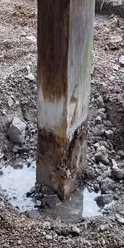 A wooden pavilion post that has deteriorated near the base