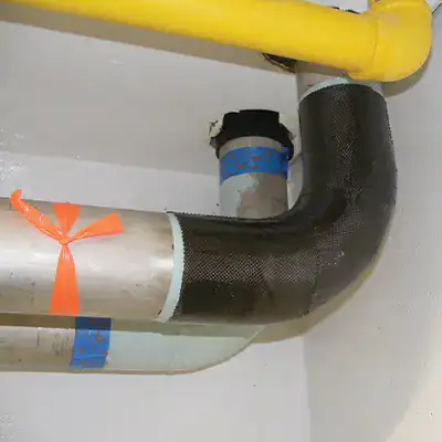 An elbow pipe wrapped with HydraWrap and another elbow pipe coated in epoxy