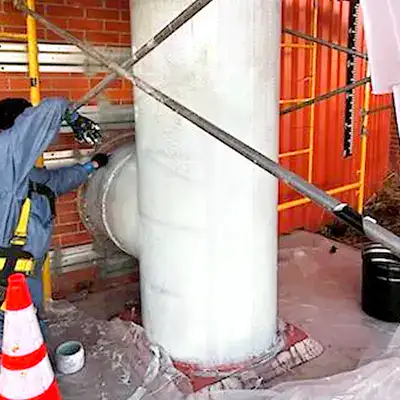A technician applying epoxy to the exterior of a vertical digester mixing pipe