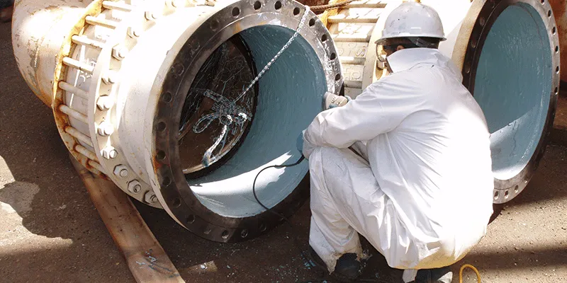 A technician looking into a cooling water pipeline that has been coated in epoxy
