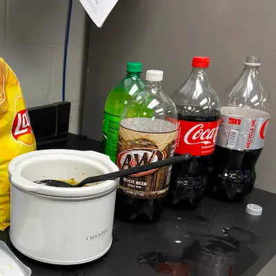 Several 2-liters sitting on a counter near a small crock pot