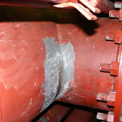 A corner of a tee fitting in a copper nickel pipe that has had the surface ground clean
