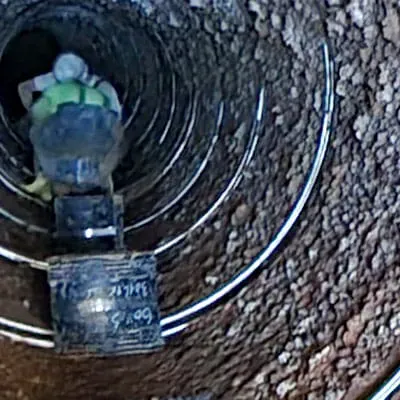 Technicians sitting in a pipe near HydraTite seal materials sitting on the invert