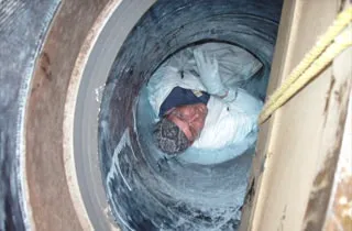 A technician working inside a cooling water pipeline, coating the inner walls in epoxy