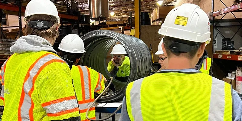Several technicians watching a HydraTite installation demo