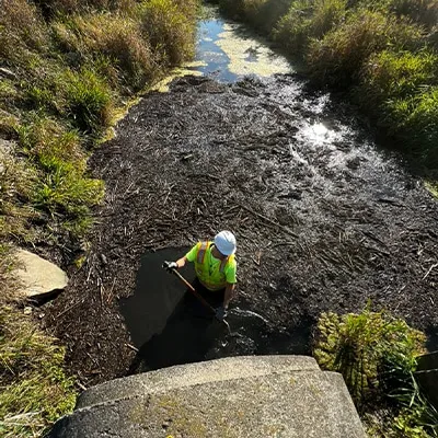 Looking down on a technician standing in deep water near a culvert entrance