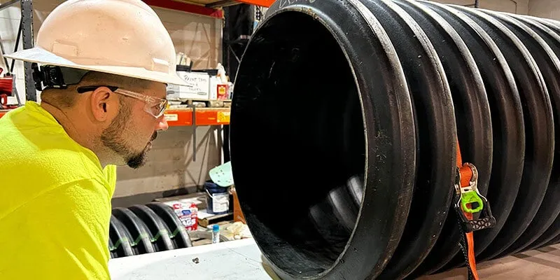 A technician looking into a demo segment of pipe