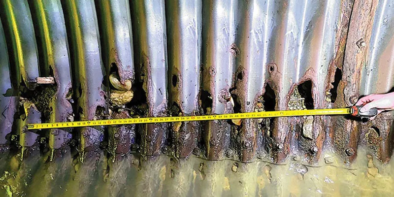 Using a measuring tape to determine the size of a deteriorated portion of this corrugated pipe's invert