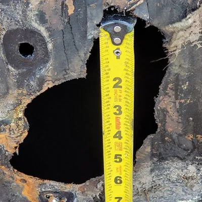 A measuring tape being used to measure a large hole in a pipe