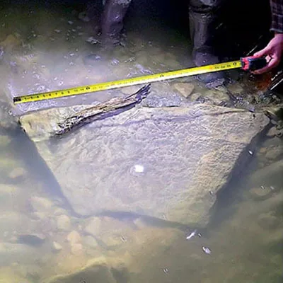 Measuring a large rock laying on the invert of a culvert
