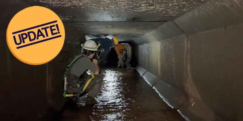 A technician squatting in a box-shaped culvert