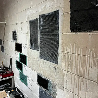 Many epoxy and fiber wrap patch repairs applied to a concrete wall for practice