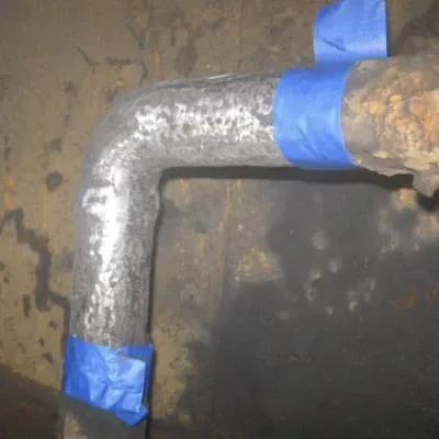 An old elbow pipe that has been ground clean and taped off for repair