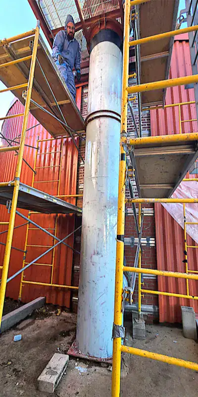A technician applying epoxy to the exterior of a vertical digester mixing pipe