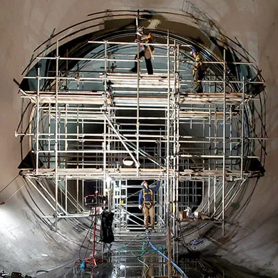 Technicians working atop scaffolding to installing HydraTite over a joint in a large diameter pipe