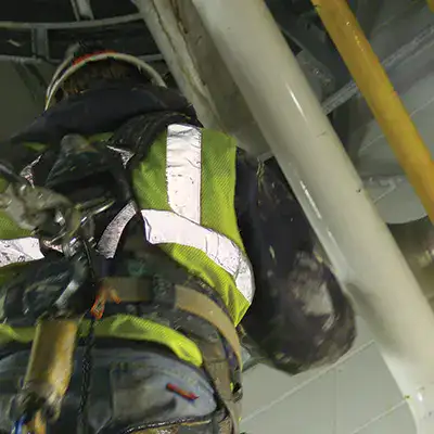 A technician up on a ladder working on pipes