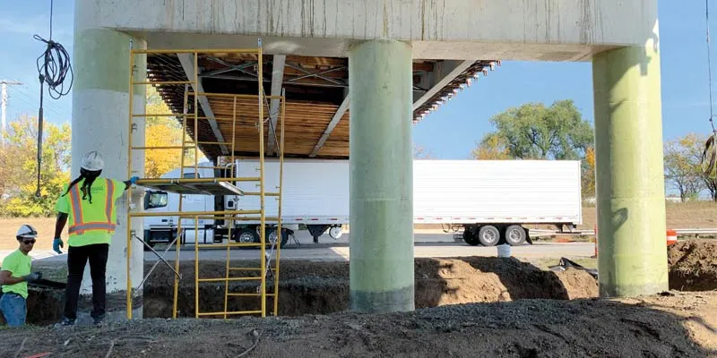Two technicians working under a bridge to reinforce the columns