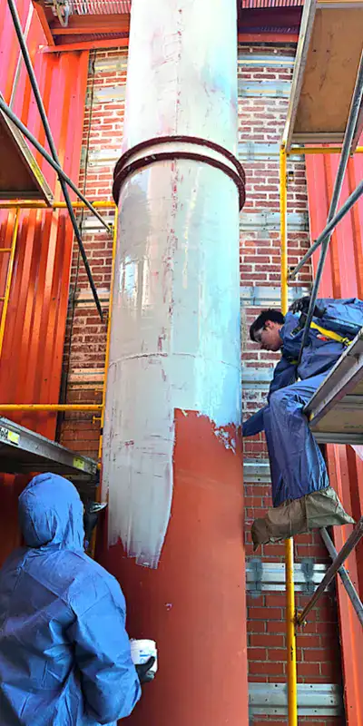 Two technician applying epoxy to the exterior of a vertical digester mixing pipe