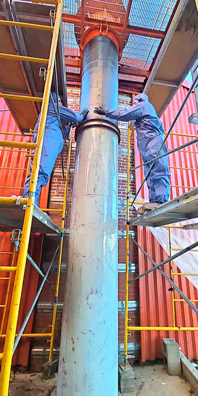 Two technician applying epoxy to the exterior of a vertical digester mixing pipe