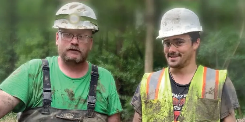 Two technicians who are dirty from working in a concrete culvert