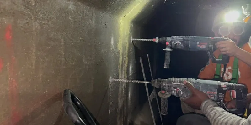 Two technicians drilling holes for the anchors that will be used in the installation of a HydraTite seal