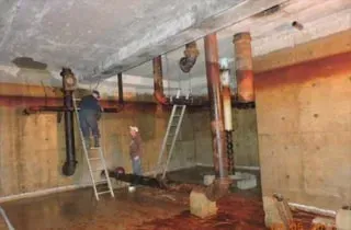 Two people working on an old pipe