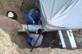 Two technicians applying epoxy to the exterior of a gas pipeline