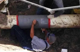 Two technicians working under a tent to restore a gas pipeline