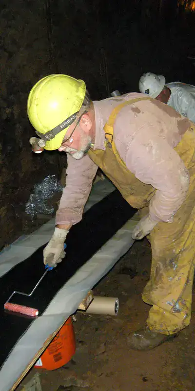 A technician saturating carbon fiber fabric in epoxy so that it can be applied to the exterior of a pipe