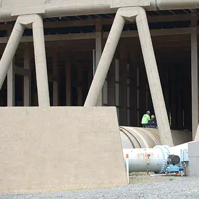 A technician working atop a large circulating water pipe