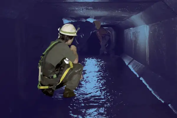 A technician squatting in a box-shaped culvert
