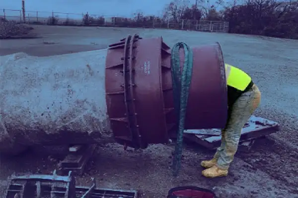 A technician reaching into a pipe that is above ground