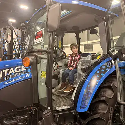 A small child sitting in the cabe of a tractor